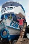 A dock worker carrying a refrigerator onto a river boat in the port of Manaus.